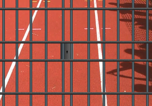 image of a running track behind prison bars