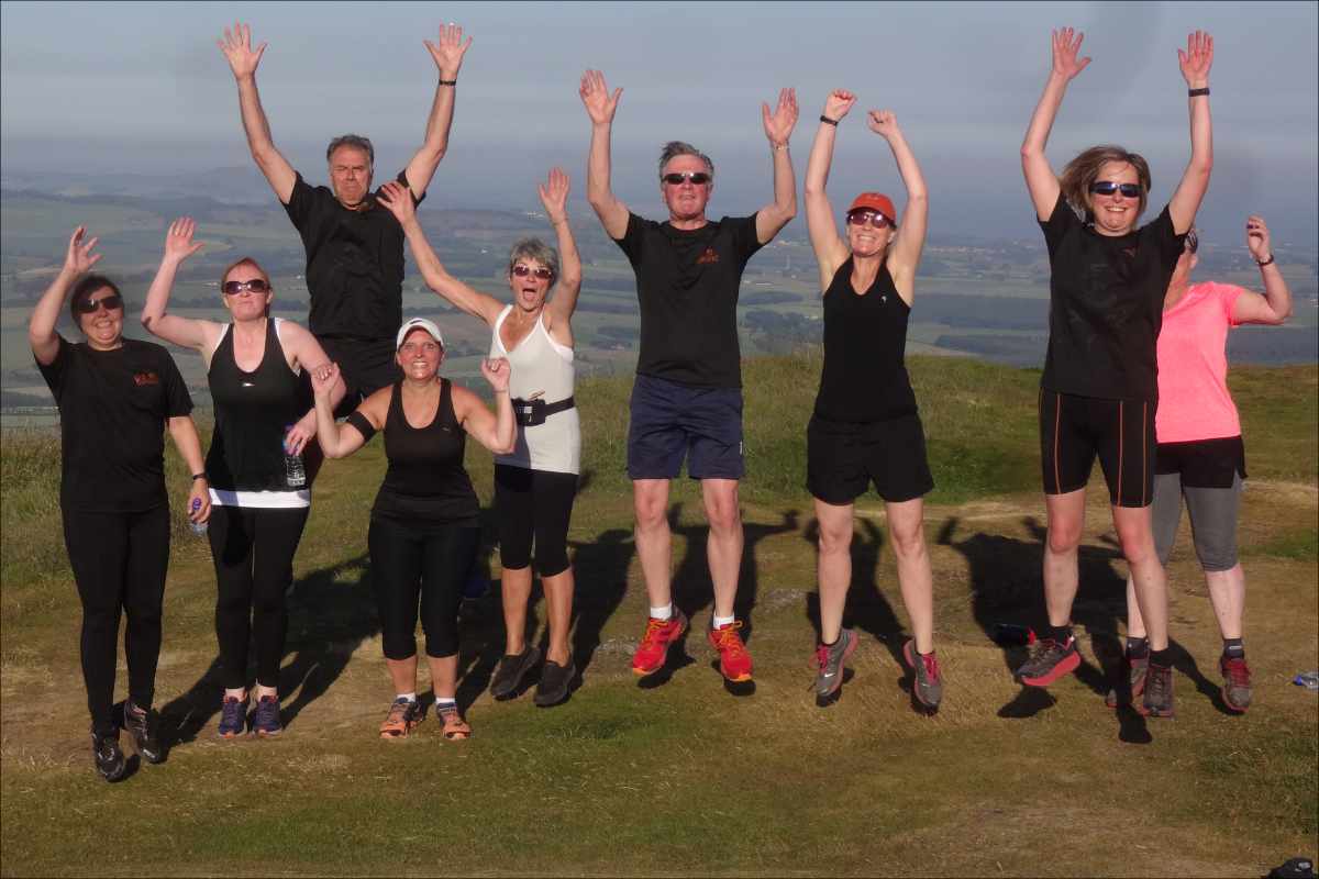 photo of a group of Couch to 5K graduates jumping up and raising their arms to the sky.