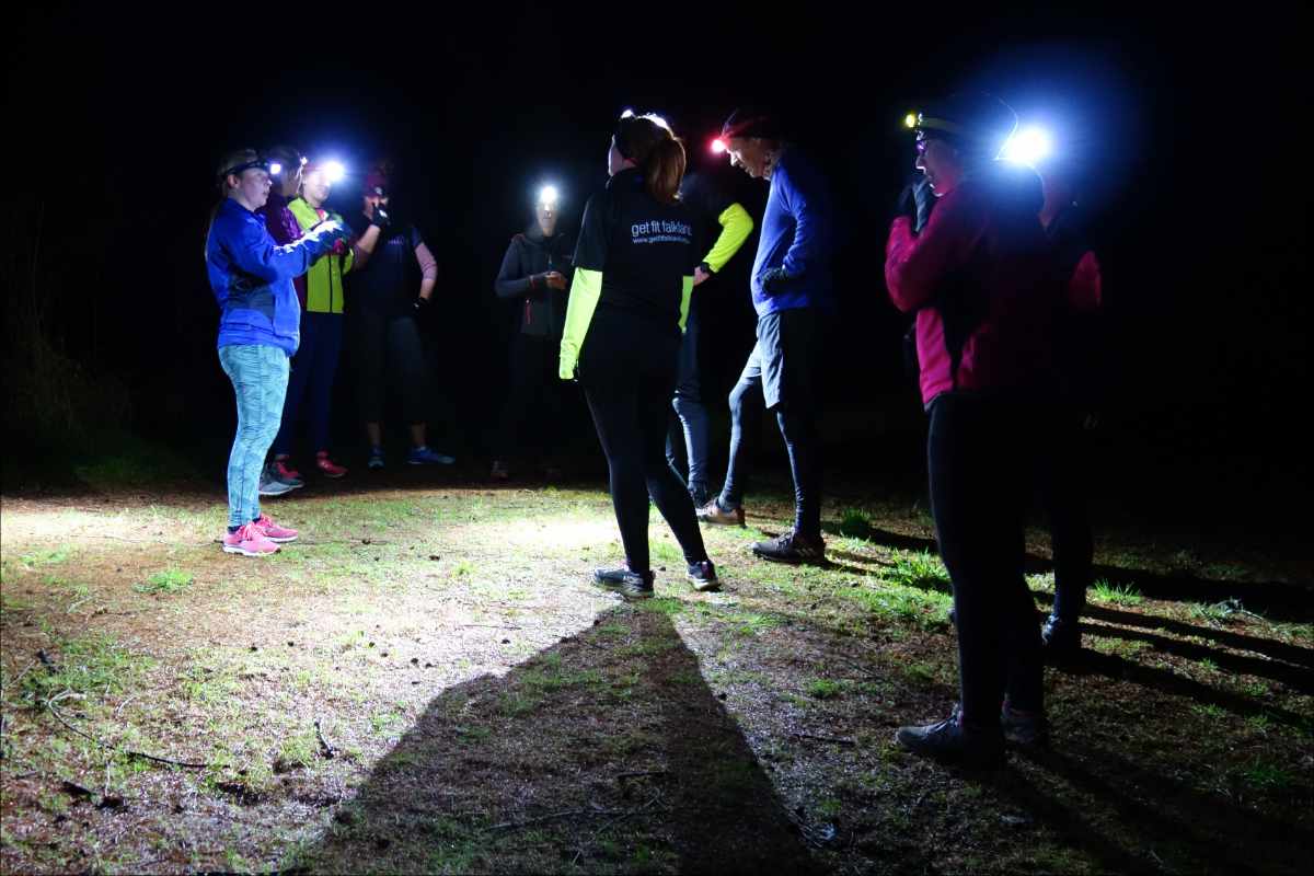 photo of a group of runners taking a short break during a run through the woods at night.
