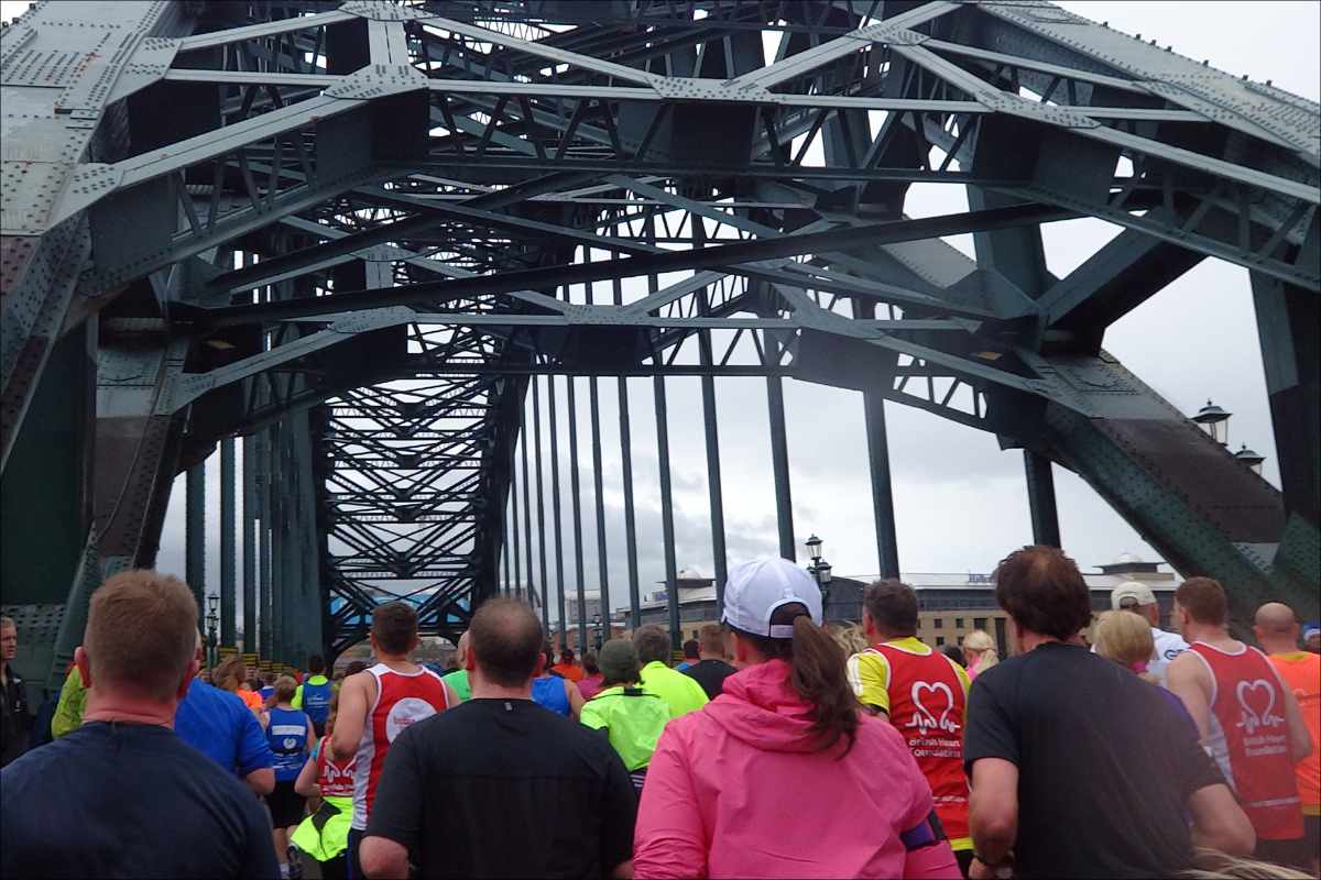 photo of runners passing under the iron superstructure of the Tyne Bridge in Newcastle.