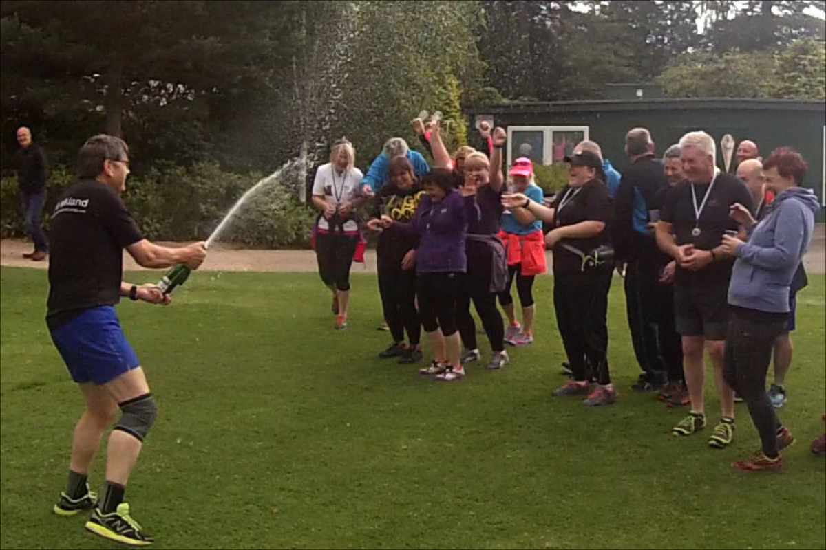 photo of a group of Couch to 5k graduates celebrate by spraying a bottle of fizz.