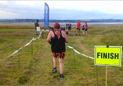 photo of a runner passing a sign saying finish, following the path between tapes..