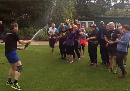 photo of a group of Couch to 5k graduates celebrate by spraying a bottle of fizz.